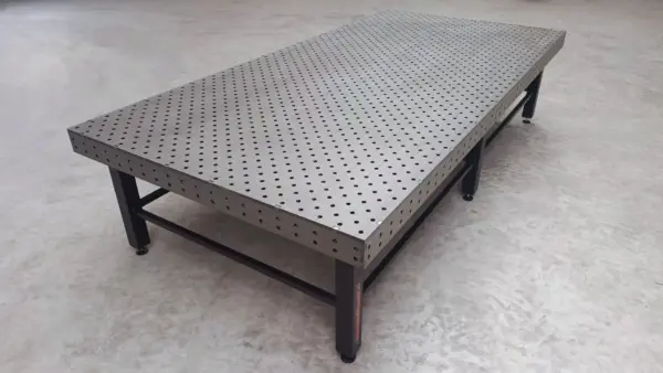 Grote industriële lastafel met gatenpatroon en opspansysteem voor nauwkeurig laswerk en staalconstructies in een professionele metaalwerkplaats.